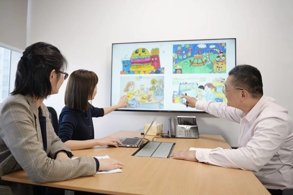  DIC China employees viewing children’s artwork on a monitor