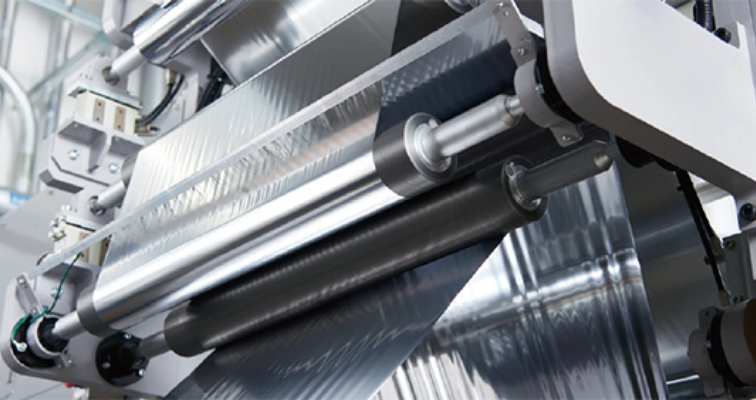 Industrial lamination machine processing transparent film, representing next-generation solvent-free lamination technology for packaging applications.