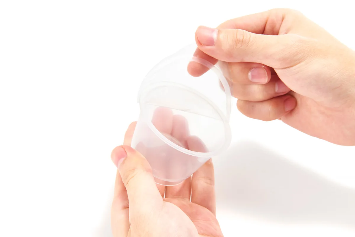 Hand peeling the lid film off a fruit cup