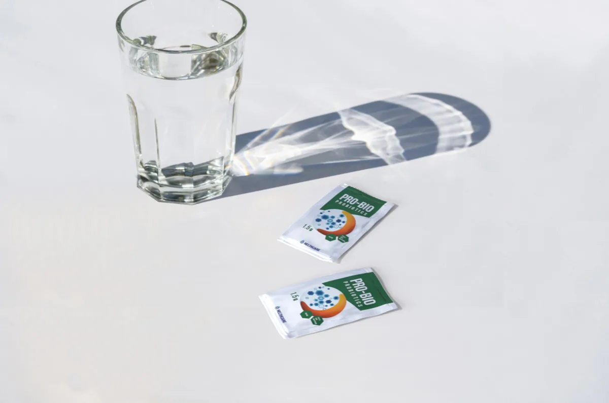 Two small pharmaceutical sachets beside a glass of water