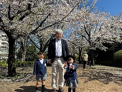 桜の木の下で並んで歩く家族の様子